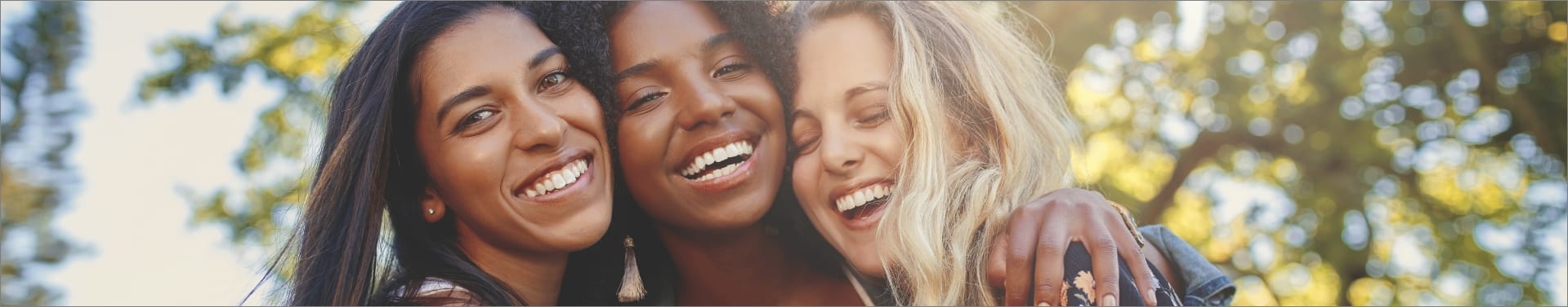 Three women laughing and smiling during a sunny summer day